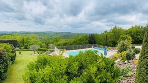 Une piscine entourée d’une végétation luxuriante, avec une vue sur des collines lointaines.