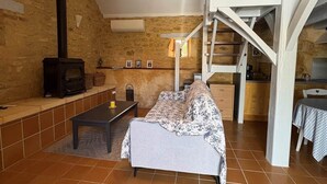 Un salon de style industriel, avec un mur en pierre, une cheminée, un canapé, une table à manger et un escalier.