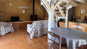 Un intérieur rustique comprenant un coin repas, un canapé, un téléviseur et un escalier.