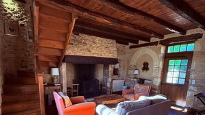 A rustic interior with a stone fireplace, wooden beams, and a stone wall. - L'écrin de verdure*Vue imprenable*Piscine (Cénac-et-Saint-Julien)