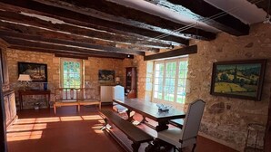 A rustic dining area with exposed wooden beams, a long table with benches, and stone walls. - L'écrin de verdure*Vue imprenable*Piscine (Cénac-et-Saint-Julien)