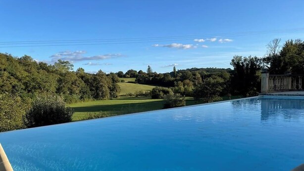 A clear blue swimming pool with a view of a green landscape and a building in the background. - L'écrin de verdure*Vue imprenable*Piscine (Cénac-et-Saint-Julien)