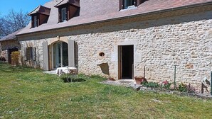A stone building with a small garden, a table, and a door. - Les Tavernes*Authentic*Calm*Pool (Daglan)