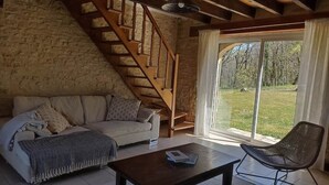 A cozy room with a stone wall, a wooden staircase, a sofa, a coffee table, and a chair. - Les Tavernes*Authentic*Calm*Pool (Daglan)