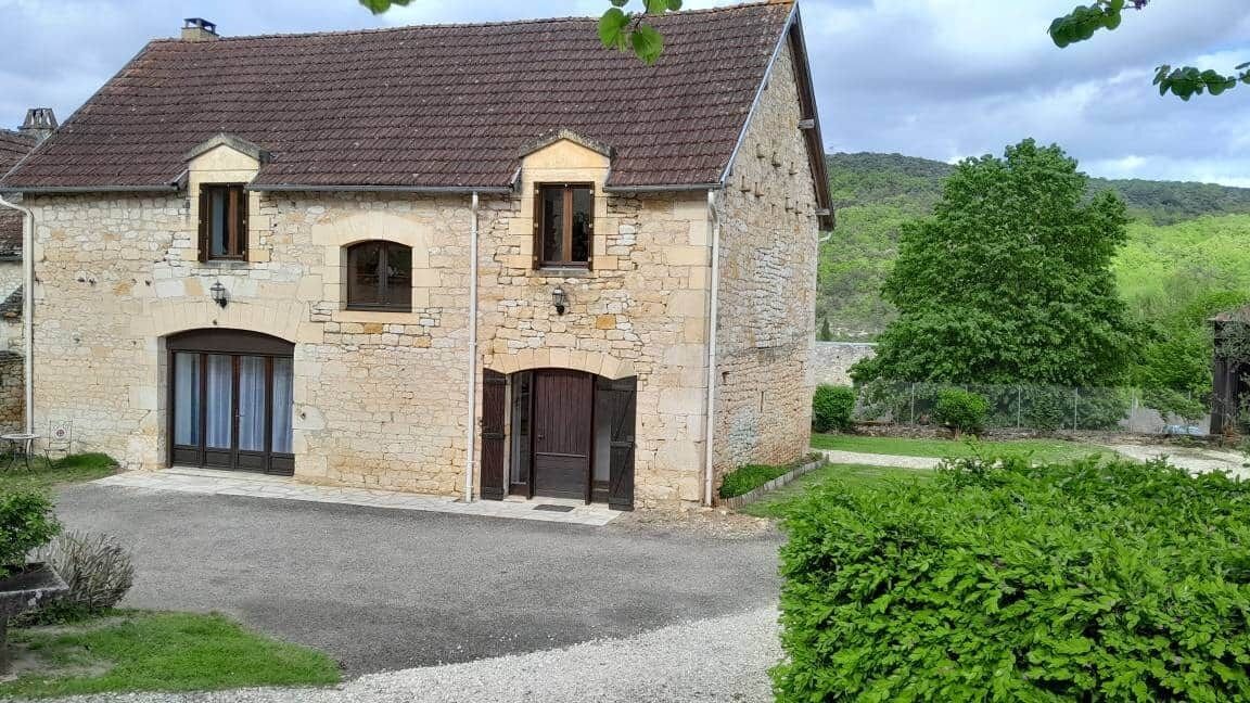 Un bâtiment en pierre avec un toit recouvert de tuiles, deux fenêtres et une porte.
