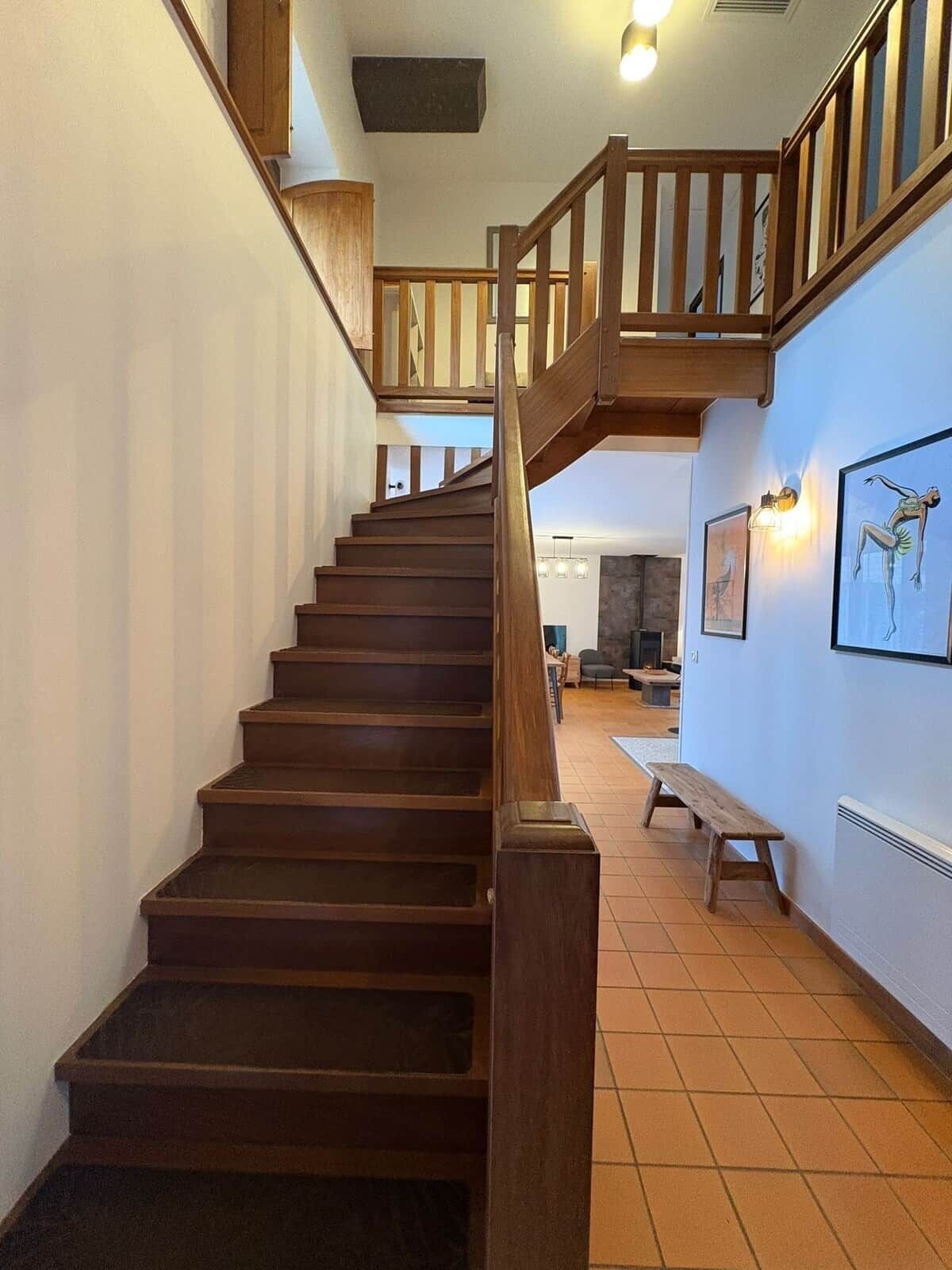 Una escalera de madera con barandilla que sube a un segundo piso.