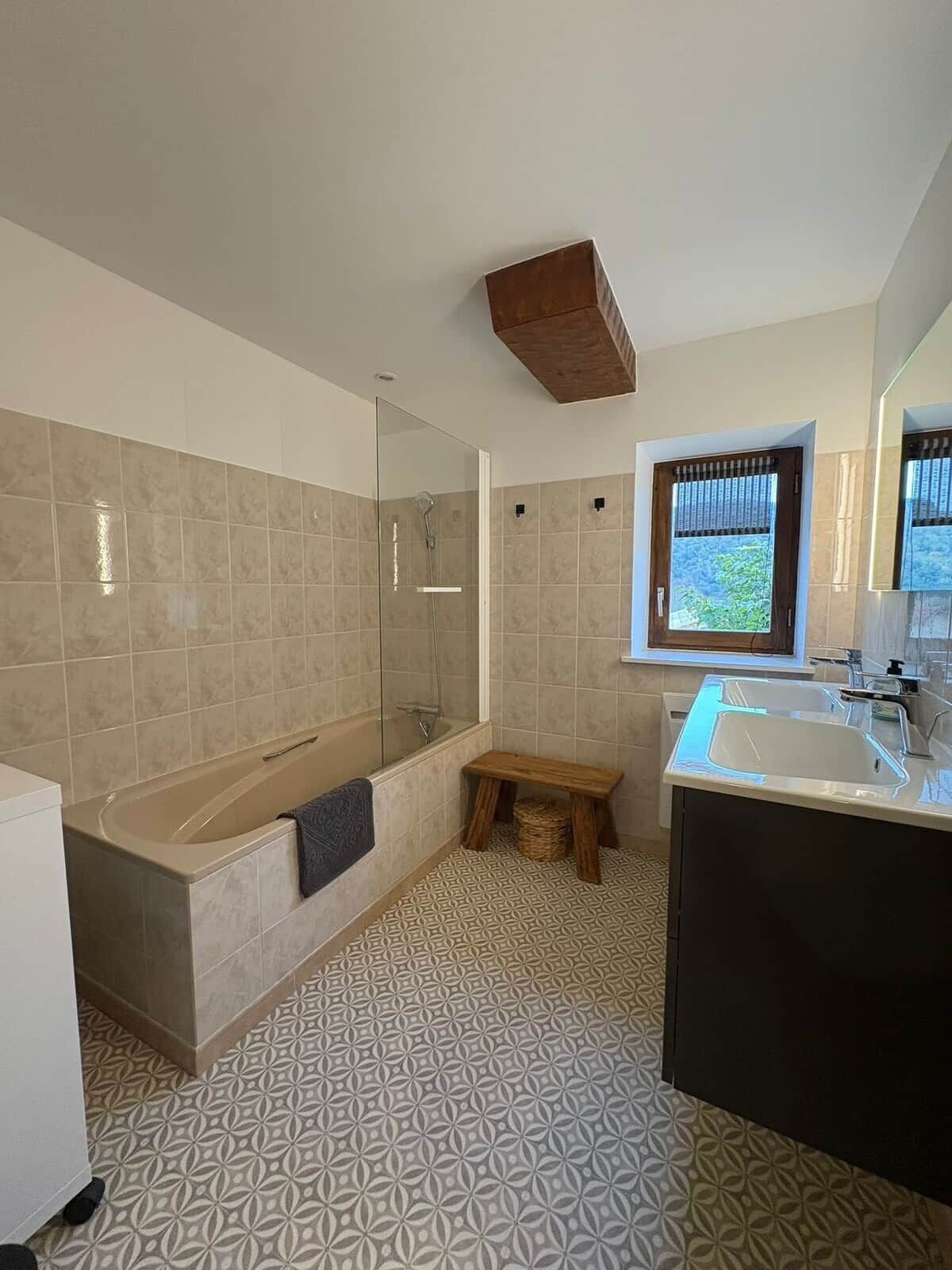 Une salle de bain moderne avec une baignoire, un meuble-lavabo avec un miroir et des carreaux de sol à motifs.
