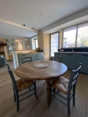 Un coin repas comprenant une table ronde en bois, quatre chaises et une assiette décorative.