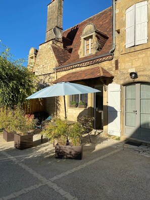 Un bâtiment en pierre avec un toit en tuiles, une porte et une fenêtre avec des volets.