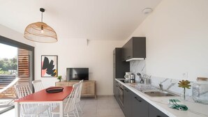 A modern kitchen with a dining area, a television, and a view of the outdoors. - Parenthèse Grand Air* Centre historique* parking lot (Sarlat-la-Canéda)