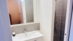 A bathroom with a white vanity, a mirror, a sink, and a shower area. - Parenthèse Grand Air* Centre historique* parking lot (Sarlat-la-Canéda)