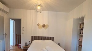 A bedroom with a large bed, a hanging light fixture, and a bookshelf. - Maison spacieuse* Jacuzzi* Proche cœur historique (Sarlat-la-Canéda)
