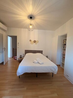 A bedroom with a large bed, a hanging light fixture, and a bookshelf. - Maison spacieuse* Jacuzzi* Proche cœur historique (Sarlat-la-Canéda)