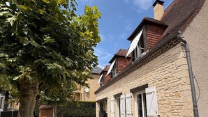 A stone building with a covered walkway, a tree, and a clear sky. - Maison spacieuse* Jacuzzi* Proche cœur historique (Sarlat-la-Canéda)