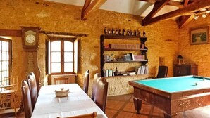 A dining area with a table, chairs, a clock, a bookshelf, and a pool table. - Nature and Charm*Pool*Beynac (Beynac-et-Cazenac)