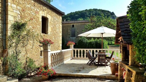 A stone building with a patio, outdoor seating, and a view of a hill. - Nature and Charm*Pool*Beynac (Beynac-et-Cazenac)