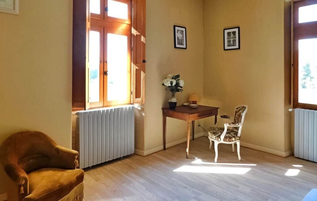 Ett rum med en trästol, ett bord med en vas och två inramade tavlor på väggen.