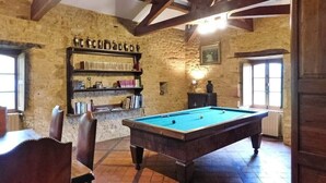 A room with a pool table, wooden chairs, a bookshelf, and stone walls. - Nature and Charm*Pool*Beynac (Beynac-et-Cazenac)