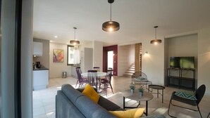 Uma sala de estar moderna com sofá, mesa de jantar, cadeiras e televisão.