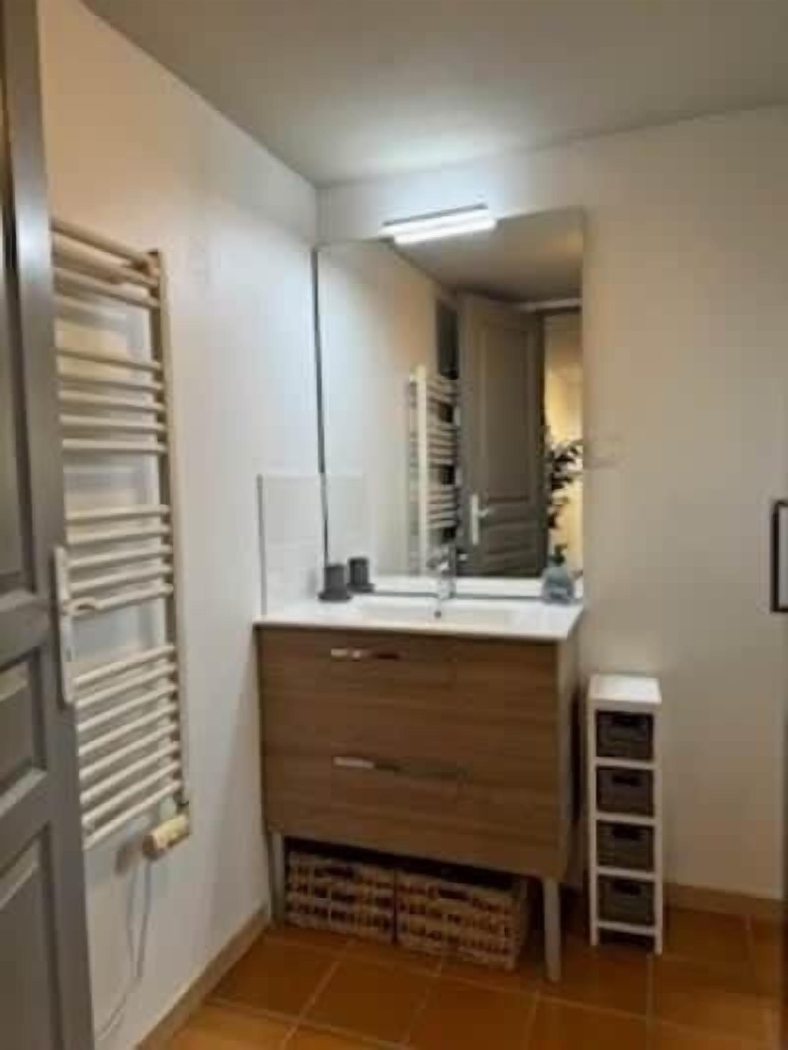 Een badkamer met een spiegel, wastafel en opbergkasten.