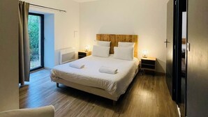 Ein modernes Hotelzimmer mit einem großen Bett, Nachttischen, einem Kleiderschrank und Blick auf Grünflächen.