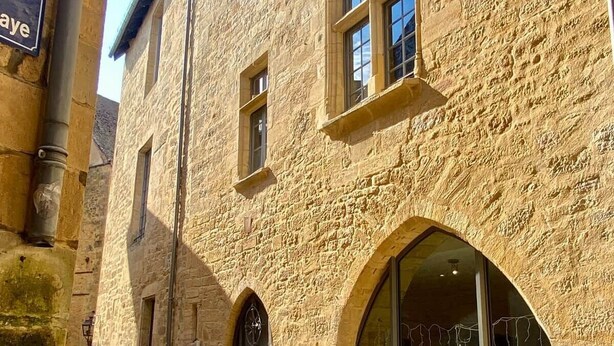Un edificio de piedra con ventanas arqueadas y la entrada a una tienda.