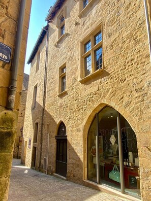 A stone building with arched windows and a shop entrance. - Sarlat Héritage * rated 3 stars (Sarlat-la-Canéda)