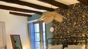 Un dormitorio con cama, ventana, un reloj de pared y un espejo.