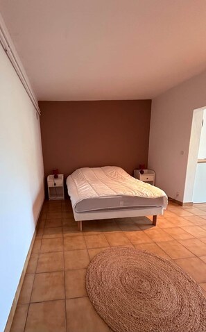 Ein Schlafzimmer mit einem Bett, zwei Nachttischen, einem Teppich und einem Fenster.