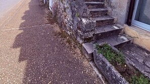 Um edifício de pedra com uma escadaria de madeira que leva a uma porta escura.
