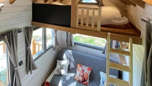 Ein Schlafzimmer im Loft-Stil mit Etagenbett, Vorhängen an einem Fenster und einem Dachfenster.