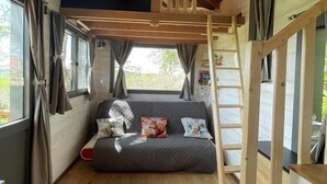Ein gemütliches Zimmer mit Schlafkoje, einer Couch, Holzbalken und großen Fenstern.