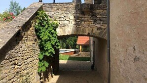 Un chemin de pierres mène à un bâtiment sur lequel est installé un parasol rouge.