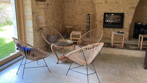 Une pièce chaleureuse avec des fauteuils en osier, une petite table ronde, une cheminée et un téléviseur fixé au mur.
