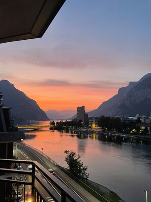 A river with mountains in the background, a bridge, and buildings along the riverbank. - The Terrace on the Adda – Apartment with Lake and Mountain View (Malgrate)