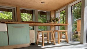 Una cocina moderna con amplios ventanales, una encimera de madera y un armario verde.