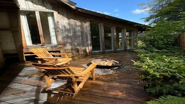 Una terraza de madera con mobiliario exterior y una chimenea.