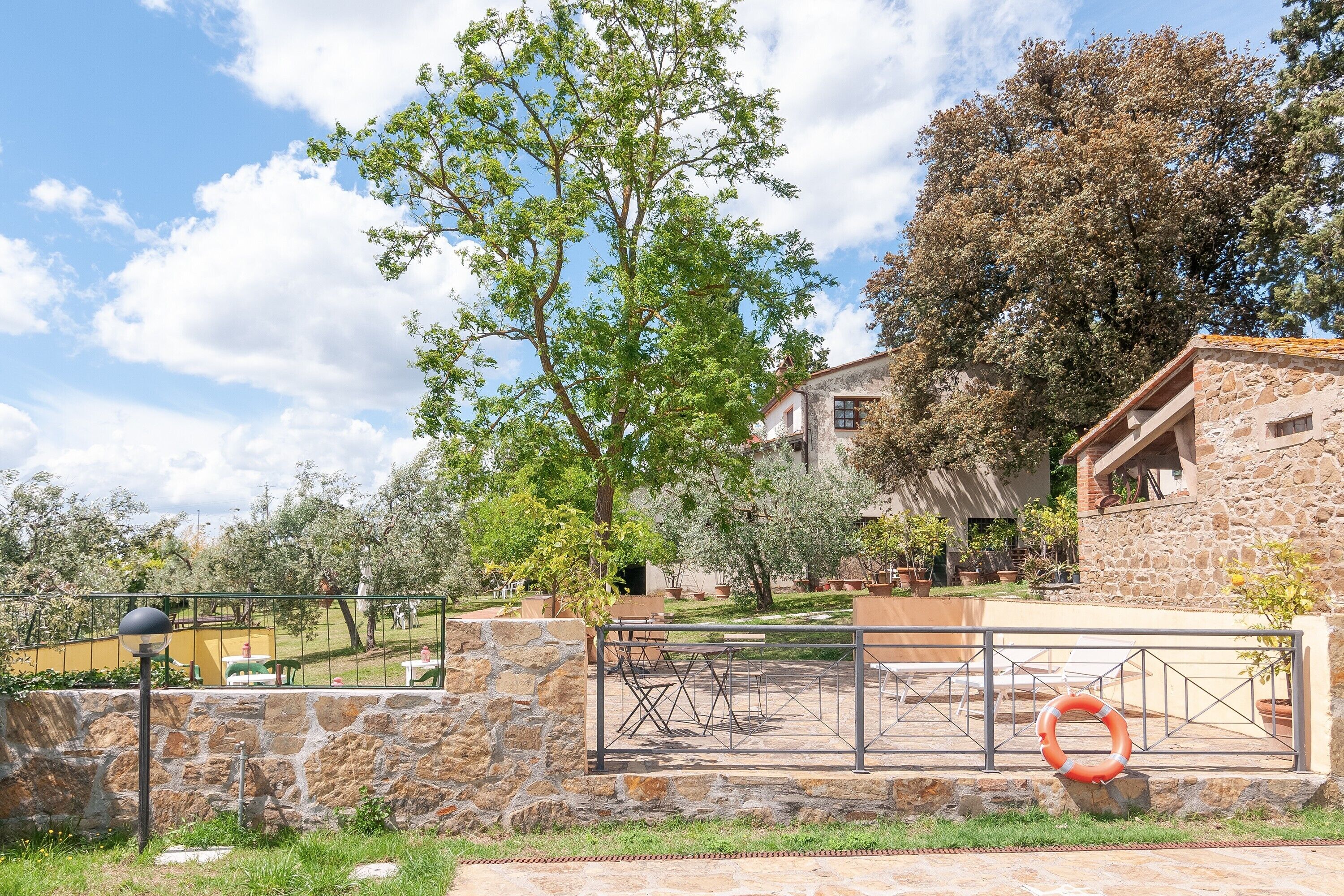 A stone building with outdoor seating, a stone wall, and a large tree.