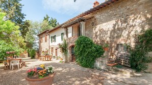 Un edificio in pietra con un cortile, posti a sedere all'aperto e piante in vaso.