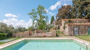 Una piscina con piastrelle in pietra, un muro in pietra e una porta in legno.