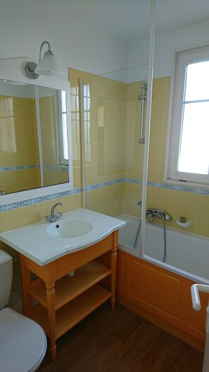Een badkamer met een wit wastafelmeubel, een spiegel, een douche en een raam.