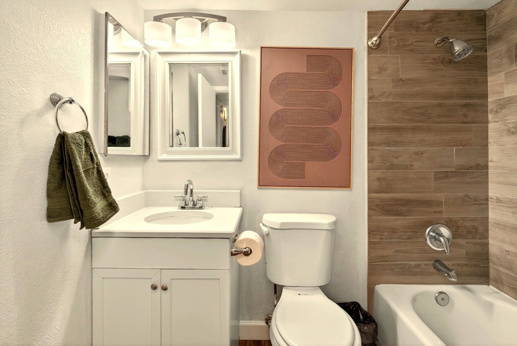 Ein Badezimmer mit Waschbecken, Toilette und Badewanne, mit einem Handtuch an der Wand.