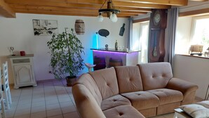 A living room with a beige sofa, a white cabinet, a potted plant, and a wooden ceiling.