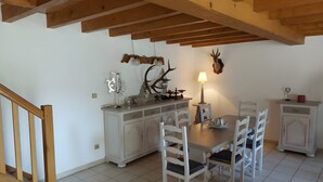 A dining area with a wooden table and chairs, a chandelier, and a wall-mounted deer head.