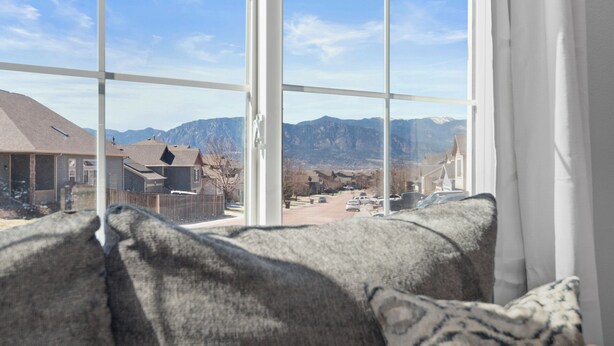 Blick aus dem Fenster auf eine Wohngegend mit Häusern, einem Gebirge und einem klaren Himmel.