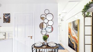 Un comedor con una puerta blanca, un arreglo de espejos en la pared y una mesa dispuesta para dos.