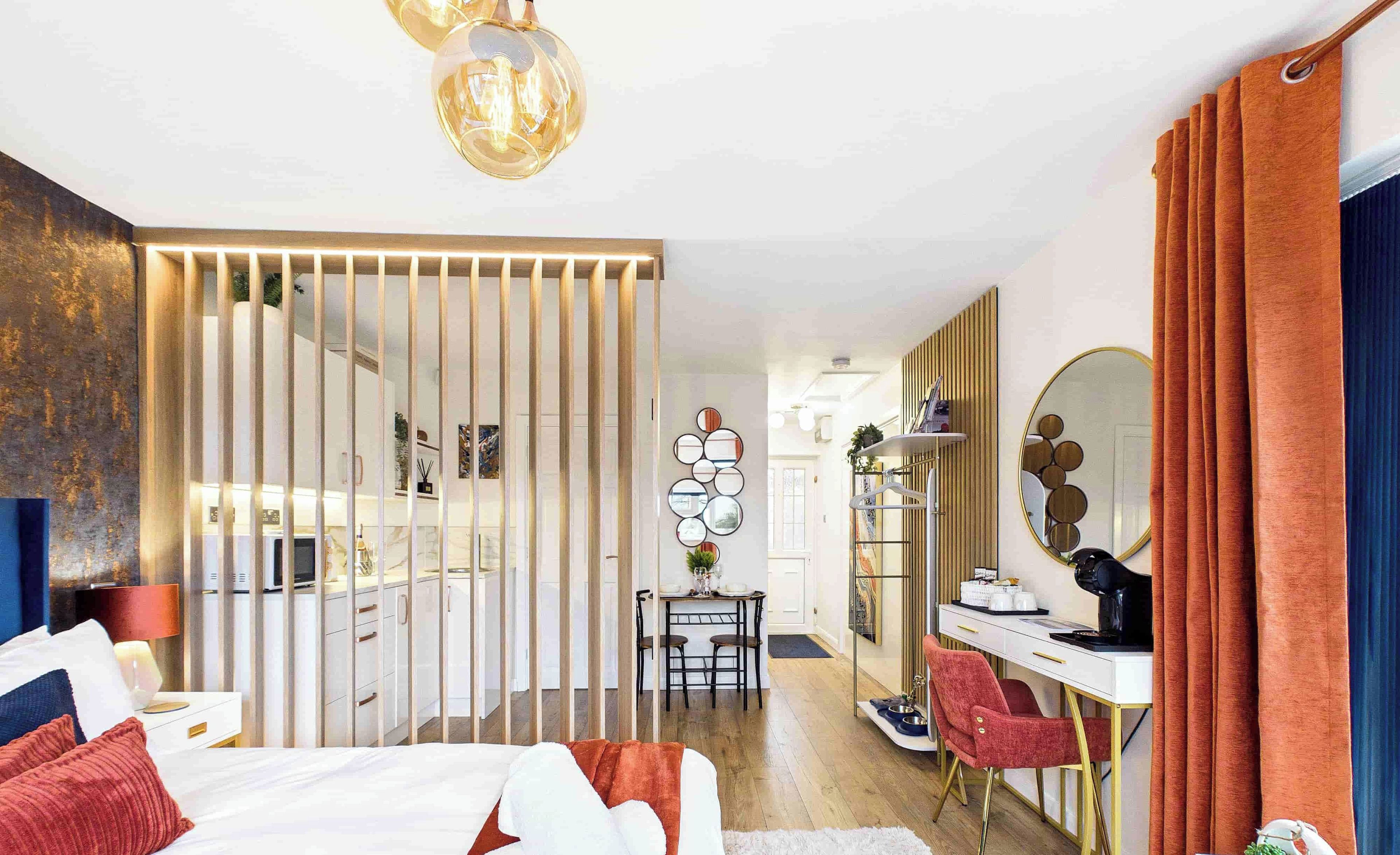 A modern bedroom with a bed, a desk, and a vanity with a mirror.
