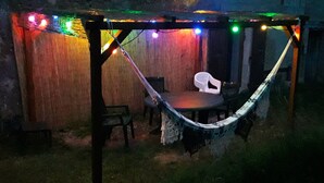 A hammock under a wooden pergola with string lights, a table, and chairs. - Vacation home near the lake, ideal for families (Montferrat)