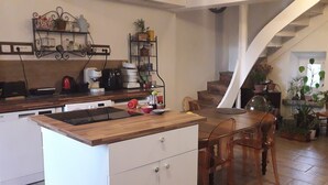 A kitchen with wooden countertops, a dining table, chairs, a staircase, and potted plants. - Vacation home near the lake, ideal for families (Montferrat)