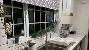 A modern kitchen with a double sink, a built-in washing machine, and a patterned window blind. - The Bungalow Birmingham NEC Airport Bullring (Birmingham)